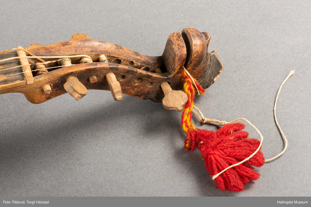 a) fele, b) bue, c) felekasse.  Bjerk, meget defekt resonanskasse.  Oversiden brukket i 3 løse deler.  Et stort stykke mangler.  Resonansbunnen lakkert, har malte profiler.  Har bare tre strenger.  Mangler flere nøkler.  Halsen avsluttes med utskåret løvehode.  Rød og gul ullsnor med dusk bundet fast til løvehodet.  Fingerbrettet har ingen gradering.  
b) Buen en rund pinne av gran.  I den ene enden skåret i L-form.  Feste for buestreng.  Strengen defekt.  I den andre enden er en takket jernbit festet i en snor.   Utsåret bjerkekloss festet i jerntråd.  
c) Gran, skåret.  Selve kassen består av et bredt bord, bøyd til hesteskoform og avsluttet med fire fjær til sinking i hver ende.  Sluttstykke mangler.  Bunnen laget av ett bord.  Festet til veggen med fire jernbeslag utvendig og en lærbit som erstatter et beslag.  Dette pluss ett av de andre beslagene går tvers over veggen og danner hengsler for lokket som er laget av ett bord, svakt hvelvet.   Liten k jernkrampe i lokk-kanten.  Tilsvarende i veggen.  Beslaget  på toppen av "hesteskoen" har en liten jernkrampe med jernring.  Lokk og vegger er overmalt.  Bunnfarge brun.  Veggen akantus i gult, sort , blått og hvitt.  Beslagene blåmalt.  På samme side som jernkrampe bokstaver og tall malt med gult:  KITTIL HARALSSEN 1843.  Veggen har to store hull.  Lokket har blomsterdekor i samme farge som veggene.  Innvendig brunmalt.  Stort stykke spikket bort.  18/8-64. Å Astrup

Fela er nå restaurert og satt i full stand. 5/3-1979, K.K.Nøklebye