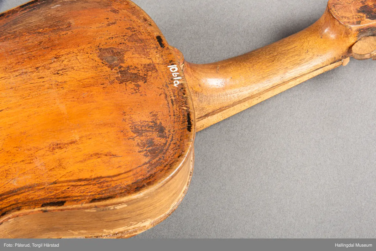 a) fele, b) bue, c) felekasse.  Bjerk, meget defekt resonanskasse.  Oversiden brukket i 3 løse deler.  Et stort stykke mangler.  Resonansbunnen lakkert, har malte profiler.  Har bare tre strenger.  Mangler flere nøkler.  Halsen avsluttes med utskåret løvehode.  Rød og gul ullsnor med dusk bundet fast til løvehodet.  Fingerbrettet har ingen gradering.  
b) Buen en rund pinne av gran.  I den ene enden skåret i L-form.  Feste for buestreng.  Strengen defekt.  I den andre enden er en takket jernbit festet i en snor.   Utsåret bjerkekloss festet i jerntråd.  
c) Gran, skåret.  Selve kassen består av et bredt bord, bøyd til hesteskoform og avsluttet med fire fjær til sinking i hver ende.  Sluttstykke mangler.  Bunnen laget av ett bord.  Festet til veggen med fire jernbeslag utvendig og en lærbit som erstatter et beslag.  Dette pluss ett av de andre beslagene går tvers over veggen og danner hengsler for lokket som er laget av ett bord, svakt hvelvet.   Liten k jernkrampe i lokk-kanten.  Tilsvarende i veggen.  Beslaget  på toppen av "hesteskoen" har en liten jernkrampe med jernring.  Lokk og vegger er overmalt.  Bunnfarge brun.  Veggen akantus i gult, sort , blått og hvitt.  Beslagene blåmalt.  På samme side som jernkrampe bokstaver og tall malt med gult:  KITTIL HARALSSEN 1843.  Veggen har to store hull.  Lokket har blomsterdekor i samme farge som veggene.  Innvendig brunmalt.  Stort stykke spikket bort.  18/8-64. Å Astrup

Fela er nå restaurert og satt i full stand. 5/3-1979, K.K.Nøklebye