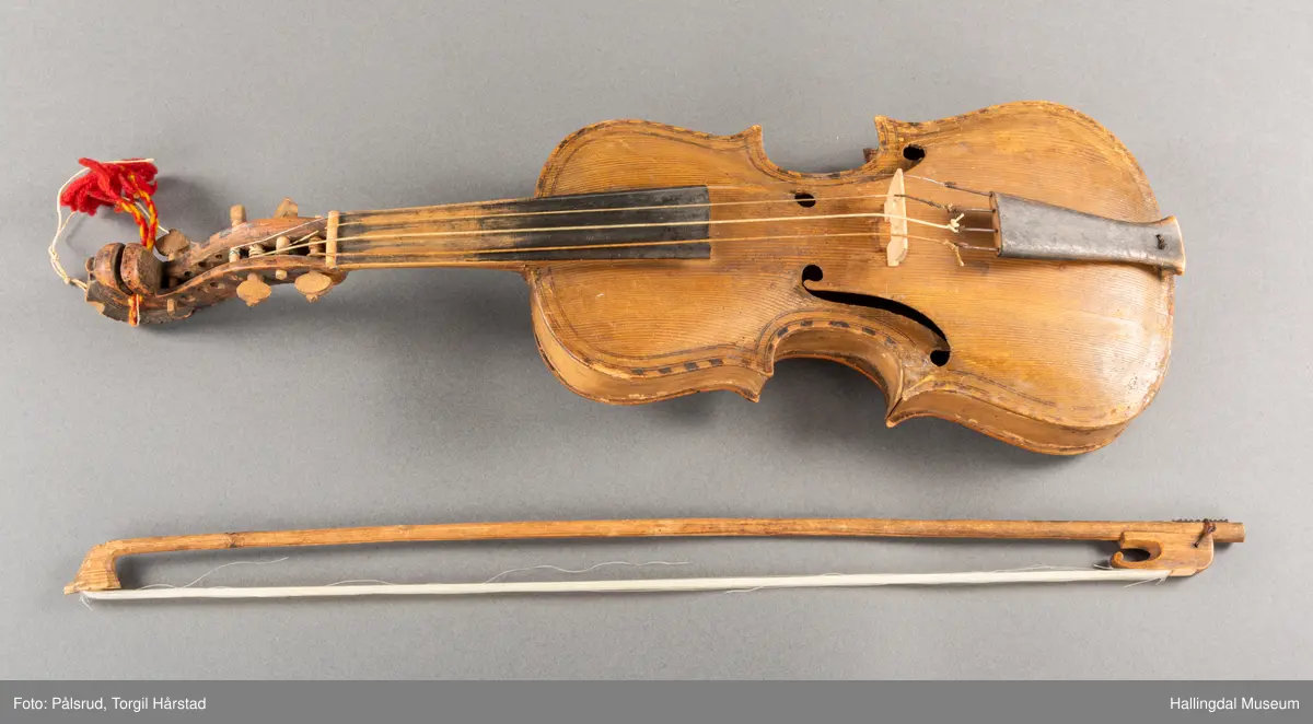 a) fele, b) bue, c) felekasse.  Bjerk, meget defekt resonanskasse.  Oversiden brukket i 3 løse deler.  Et stort stykke mangler.  Resonansbunnen lakkert, har malte profiler.  Har bare tre strenger.  Mangler flere nøkler.  Halsen avsluttes med utskåret løvehode.  Rød og gul ullsnor med dusk bundet fast til løvehodet.  Fingerbrettet har ingen gradering.  
b) Buen en rund pinne av gran.  I den ene enden skåret i L-form.  Feste for buestreng.  Strengen defekt.  I den andre enden er en takket jernbit festet i en snor.   Utsåret bjerkekloss festet i jerntråd.  
c) Gran, skåret.  Selve kassen består av et bredt bord, bøyd til hesteskoform og avsluttet med fire fjær til sinking i hver ende.  Sluttstykke mangler.  Bunnen laget av ett bord.  Festet til veggen med fire jernbeslag utvendig og en lærbit som erstatter et beslag.  Dette pluss ett av de andre beslagene går tvers over veggen og danner hengsler for lokket som er laget av ett bord, svakt hvelvet.   Liten k jernkrampe i lokk-kanten.  Tilsvarende i veggen.  Beslaget  på toppen av "hesteskoen" har en liten jernkrampe med jernring.  Lokk og vegger er overmalt.  Bunnfarge brun.  Veggen akantus i gult, sort , blått og hvitt.  Beslagene blåmalt.  På samme side som jernkrampe bokstaver og tall malt med gult:  KITTIL HARALSSEN 1843.  Veggen har to store hull.  Lokket har blomsterdekor i samme farge som veggene.  Innvendig brunmalt.  Stort stykke spikket bort.  18/8-64. Å Astrup

Fela er nå restaurert og satt i full stand. 5/3-1979, K.K.Nøklebye