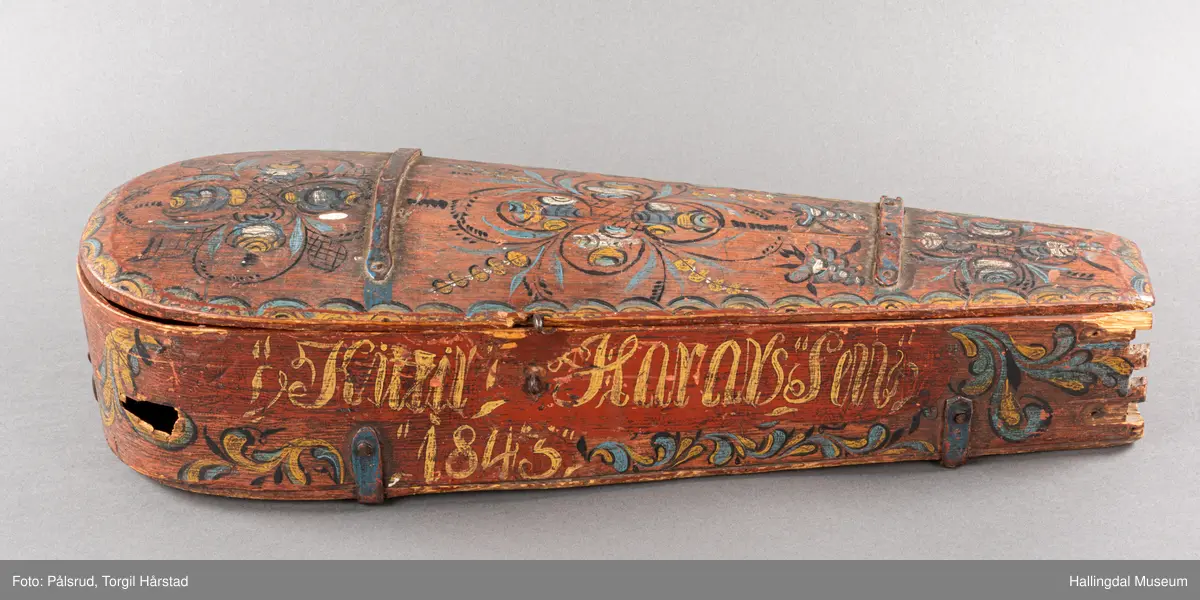 a) fele, b) bue, c) felekasse.  Bjerk, meget defekt resonanskasse.  Oversiden brukket i 3 løse deler.  Et stort stykke mangler.  Resonansbunnen lakkert, har malte profiler.  Har bare tre strenger.  Mangler flere nøkler.  Halsen avsluttes med utskåret løvehode.  Rød og gul ullsnor med dusk bundet fast til løvehodet.  Fingerbrettet har ingen gradering.  
b) Buen en rund pinne av gran.  I den ene enden skåret i L-form.  Feste for buestreng.  Strengen defekt.  I den andre enden er en takket jernbit festet i en snor.   Utsåret bjerkekloss festet i jerntråd.  
c) Gran, skåret.  Selve kassen består av et bredt bord, bøyd til hesteskoform og avsluttet med fire fjær til sinking i hver ende.  Sluttstykke mangler.  Bunnen laget av ett bord.  Festet til veggen med fire jernbeslag utvendig og en lærbit som erstatter et beslag.  Dette pluss ett av de andre beslagene går tvers over veggen og danner hengsler for lokket som er laget av ett bord, svakt hvelvet.   Liten k jernkrampe i lokk-kanten.  Tilsvarende i veggen.  Beslaget  på toppen av "hesteskoen" har en liten jernkrampe med jernring.  Lokk og vegger er overmalt.  Bunnfarge brun.  Veggen akantus i gult, sort , blått og hvitt.  Beslagene blåmalt.  På samme side som jernkrampe bokstaver og tall malt med gult:  KITTIL HARALSSEN 1843.  Veggen har to store hull.  Lokket har blomsterdekor i samme farge som veggene.  Innvendig brunmalt.  Stort stykke spikket bort.  18/8-64. Å Astrup

Fela er nå restaurert og satt i full stand. 5/3-1979, K.K.Nøklebye