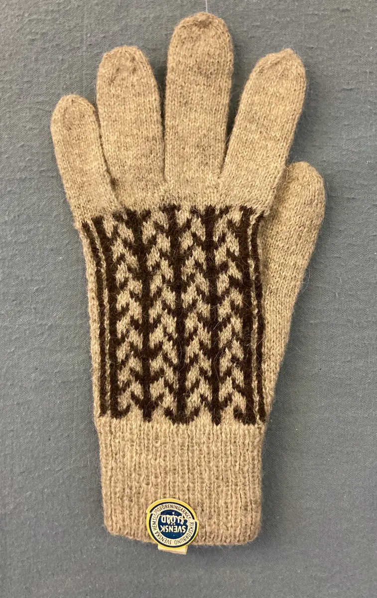 Fingervante stickad med mönster på framsidan. Märkt med etikett: Svensk Slöjd. Östergötlands Läns Hemslöjdsförening.
CD603 20 kr.
