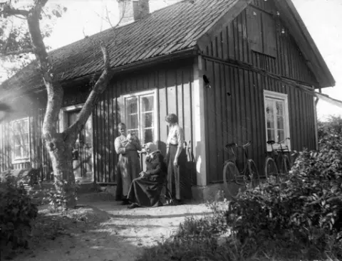 Tre kvinnor framför stuga, 1890-tal