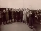 Motala Telefonstation omkr. 1925-30. Gruppbild. Stående: eltf Karin Lindquist, eltf Anna-Lisa Hilding, rtf Signe Ahlson, ltf Nelly Björkman, eltf Karin Lindeberg, tf vf Elsa Fagerberg, lntf Anna Gustavsson, tk Axel Lundholm, ltf Greta Lundquist, eltf Britta Widlund, rtf Signe Elisabeth Andersson, ltf Karin Elisabeth Andersson. I bakgrunden ltf Tyra Funge och lntf Lilly Erlandsson. Sittande från kameran räknat: ertf Tyra Danielsson,rtf Elsa Androth och rtf Astrid Gustavsson.