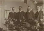 Skeppsbron 2. Uppfinnaren Donald Murray, tk Ernst Olsson, lf Petterson och tk Ad. Widstrand. Fotot taget vid installeringen i telegrafapp.salen av Myrray-systemet för exp. med Göteborg.