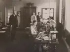 Uddevalla Telegrafstation. Interiör. Tk G.E. Olsson, eotgx S.B.C. Zetterqvist (vid telegrafbordet), ktb W.I.M. Carlsson (vid blankettskåpet), tgx E.M.M. Carlsson (vid telegrafbordet), ks F.A.M. Macfie (vid blankettskåpet).