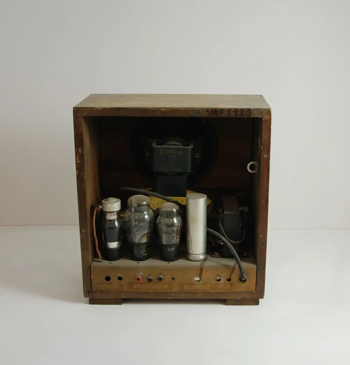 Radio, bordmodell. Rektangulær trekasse i furu med finert mørkbeiset bjørk. Fire flate klosser til bein. På frontens sider er limt to vertikale pyntelister i lys bjørk. Frontens øvre del har stofftrukket, vifteformet utsparing for høyttaler, nedenfor er en bueformet utsparing for høyttaler, nedenfor er en bueformet søkerskive i bakelittramme. Nederst er tre brune bakelittknotter for tilkobling, søker og volum.