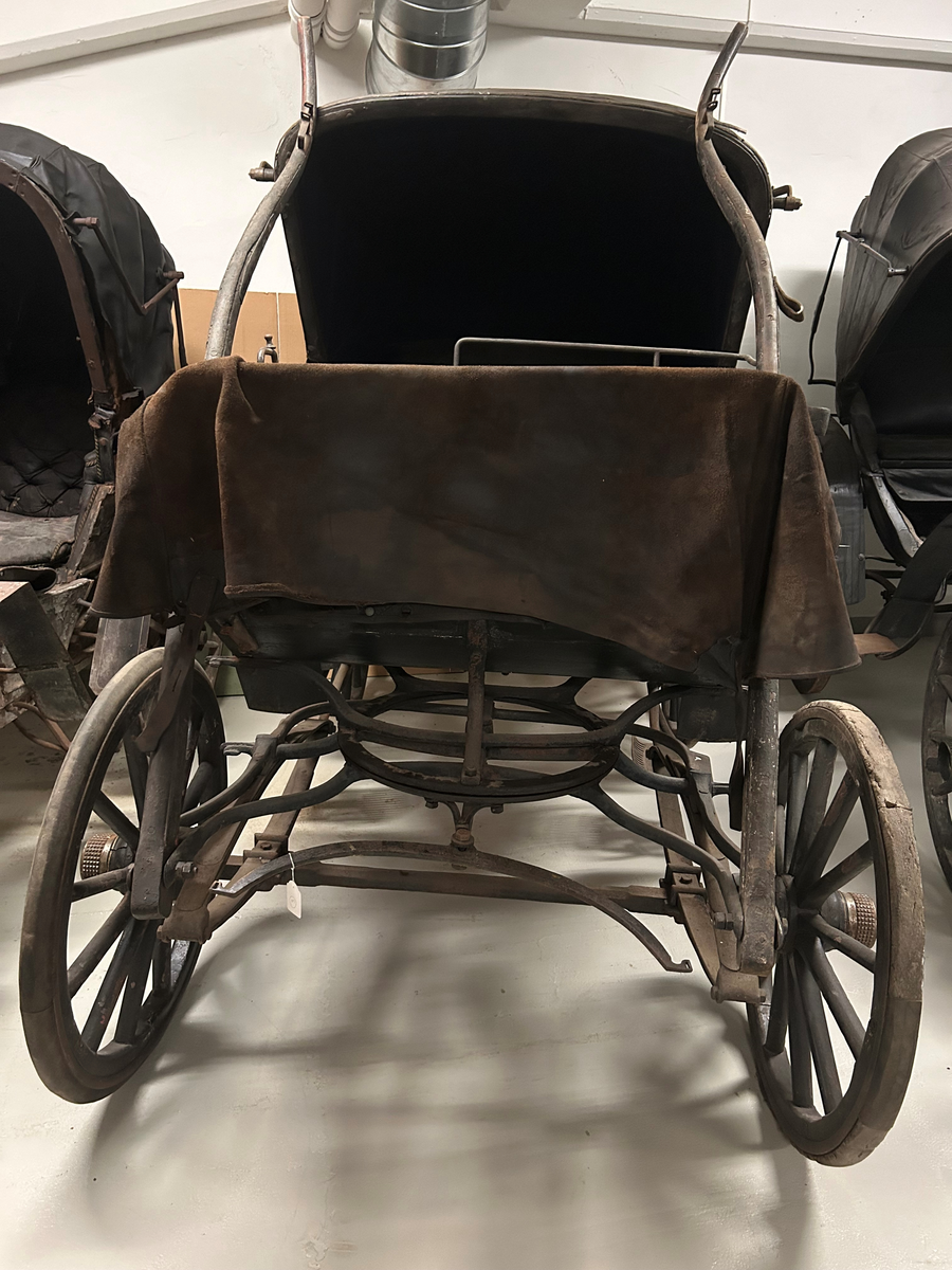 Svartmålad. Fyrhjulig hästvagn. Vagnen har öppen kuskbock med möjlighet att dra sufflett över passagerarplatsen. Huvudsäte för framåtresande men litet klätt nedfällbart säte för bakåtresande. Sätena är klädda med svart skinn. Fotsteg på varje sida.  Två skaklar framtill. Stänkskydd monterade på bakhjulen. Bakhjulen större än framhjulen.