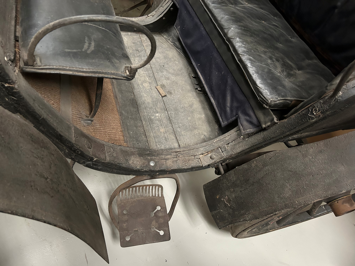 Svartmålad. Fyrhjulig hästvagn. Vagnen har öppen kuskbock med möjlighet att dra sufflett över passagerarplatsen. Huvudsäte för framåtresande men litet klätt nedfällbart säte för bakåtresande. Sätena är klädda med svart skinn. Fotsteg på varje sida.  Två skaklar framtill. Stänkskydd monterade på bakhjulen. Bakhjulen större än framhjulen.