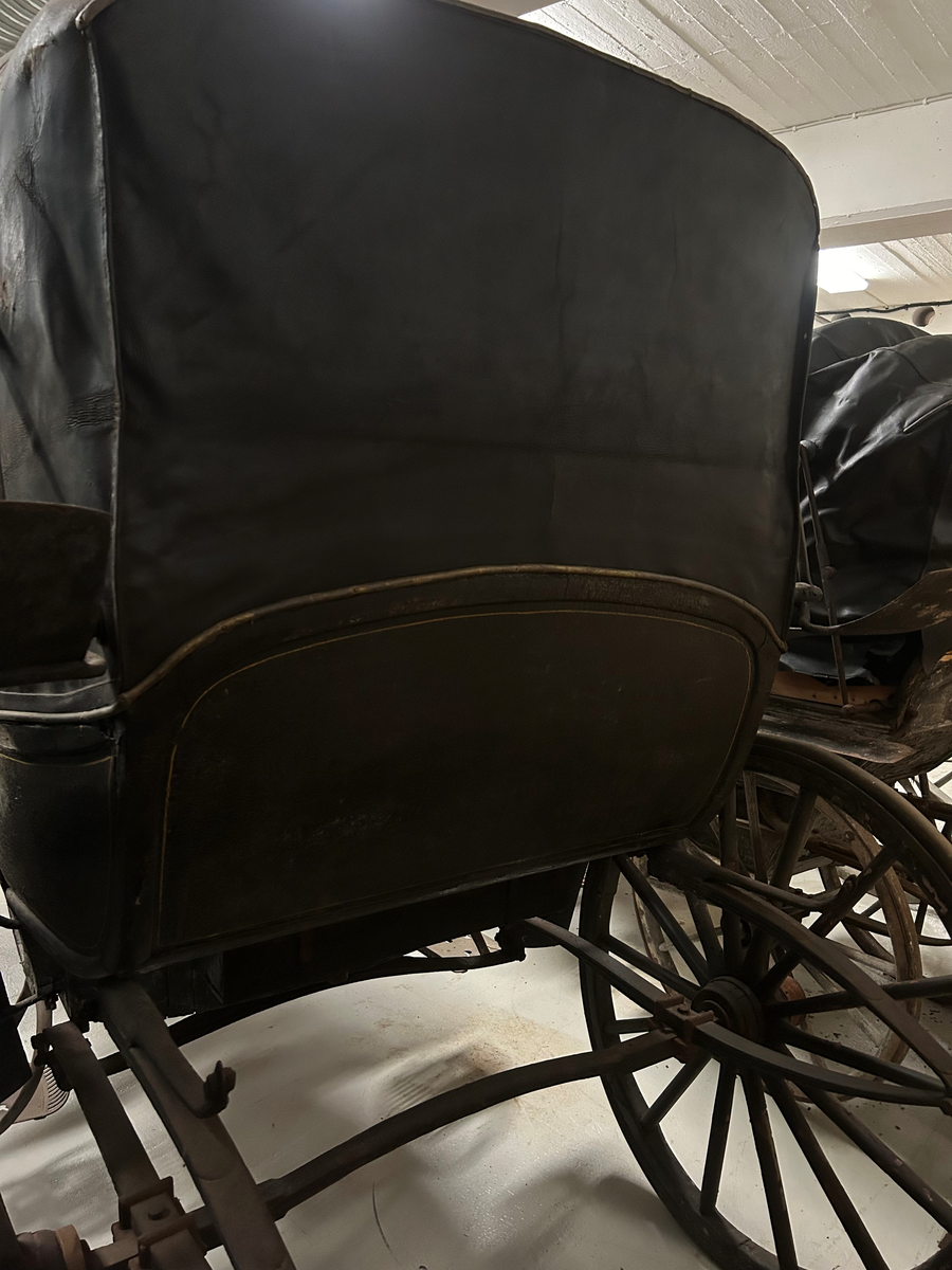 Svartmålad. Fyrhjulig hästvagn. Vagnen har öppen kuskbock med möjlighet att dra sufflett över passagerarplatsen. Huvudsäte för framåtresande men litet klätt nedfällbart säte för bakåtresande. Sätena är klädda med svart skinn. Fotsteg på varje sida.  Två skaklar framtill. Stänkskydd monterade på bakhjulen. Bakhjulen större än framhjulen.