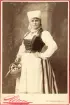Operasångerskan Christina Nilsson i Vingåkersdräkt.
Knäbild, halvprofil. Ateljéfoto. 
Under fotot text: 