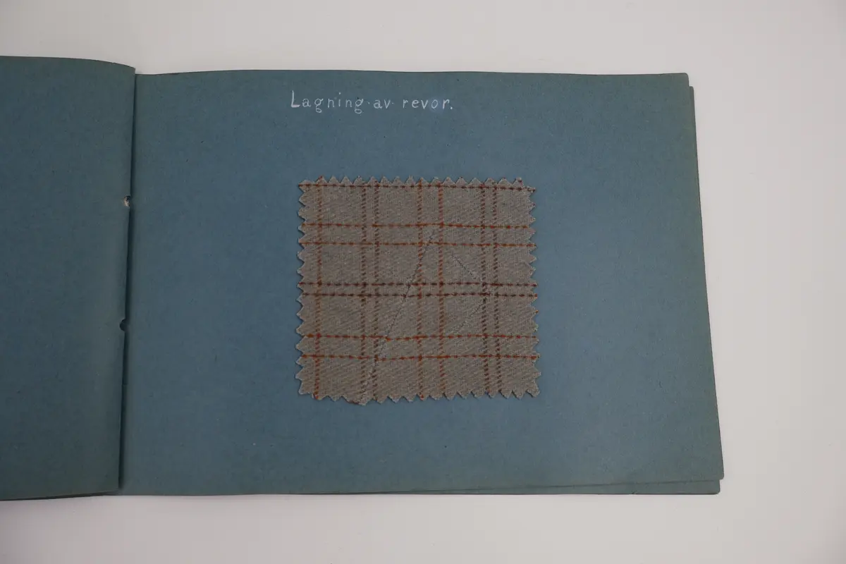 Provbok med stoppsömmar. Egenhändigt tillverkad bok av vikta ark i gråblå kartong sammanfogade med ett slitet rosa sidenband knutet i rosett. Handskriven text i vitt på framsidan: "STOPPNING  IRMA WELIN.".
- På första uppslaget, höger sida står det: "Rutstopp."
Stoppsömmen är sydd med rött ullgarn i form av en kvadrat mitt på den 120 x120 mm stora bottenväven i panamabindning. Fållad med sicksack-bård innanför fransen.
- Nästa uppslag visar prov på två två olika maskstoppar på var sin slätstickad lapp med rätstickad kant längs alla fyra sidor. Lapparna är stickade i oblekt bomullsgarn, maskstopparna i blågrått bomullsgarn i form av en kvadrat mitt på lappen. På den högra sidan står överst: "Äkta maskstopp.".
- Tredje uppslaget, till vänster ytterligare en stickad lapp i oblekt bomullsgarn. Resårstickad med rätstickad kant runt om. Maskstopp i blågrått bomullsgarn i en kvadratisk ruta mitt på lappen.
På höger sida står det med vit text: "Mönsterstopp till gåsögon.". En gles klistrad väv i vitt med mönsterstoppning i rött garn i den ena riktningen och blått garn i den andra riktningen i form av ett gåsöga. Röd broderad bård innanför fransen.
- Fjärde uppslaget, till höger; ett prov på beige gabardintyg, mönsterstoppat/konststoppat på två ställen med tråd i samma färg. Text högst upp: "Mönsterstopp-till-gabardin.".
- Nästa uppslag, till höger visar ett rutigt kostym-/dräkttyg vävt i kypert med prov på en fin lagning. Överst står det: "Lagning-av-revor.".
- Sista uppslaget, till höger visar två prover på tyllstoppning. En kvadratisk kartongbit 70 x 70 mm med två nyanser rött garn trätt upp och ned igenom kartongen till ett nät. Trädning/stopp med blått garn över halva ytan. Intill sitter en bit vit tyll med en lagning/stopp mitt på. Text överst på sidan: "Tyllstopp.".