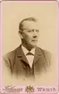 Handlanden och fabrikören m.m. Carl Schander, Växjö, i mörk kostym med väst, stärkkrage och fluga.
Bröstbild, halvprofil. Ateljéfoto.