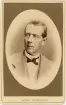 Handlanden och fabrikören m.m. Carl Schander i ljus tweedkostym med väst, stärkkrage och fluga.
Bröstbild, halvprofil. Ateljéfoto.
På baksidan text: 