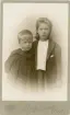 Benno Nilsson i mörk sjömansbussarong med systern Anna i enkel, mörk dräkt hos fotografen.
Midjebild. Ateljéfoto.

Anna och Benno Nilsson, barn till godsägaren m.m. Johannes Nilsson, Gådsby.