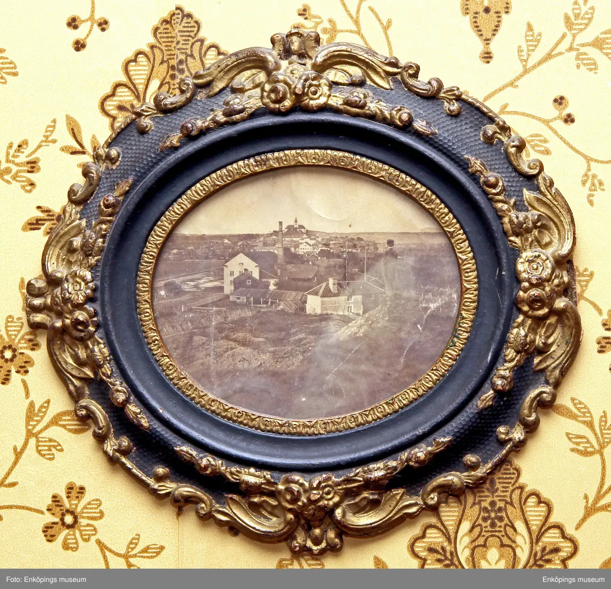 Vy över staden i början av 1860-talet, bilden är tagen från Gröngarnsåsen vid Lustigkulla. Trähuset i förgrunden till vänster är det fattighus som revs 1883. Huset bakom med den höga skorstenen är bränneriet. Framför kyrkan ses Långholmen och rådhuset och framför rådhuset Lagerströmskahuset vid torget.

Ett av de äldsta fotografierna över Enköping. Fotograf: Okänd