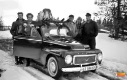 I bild en grupp skidåkare under färd med en Volvo PV 444  (r