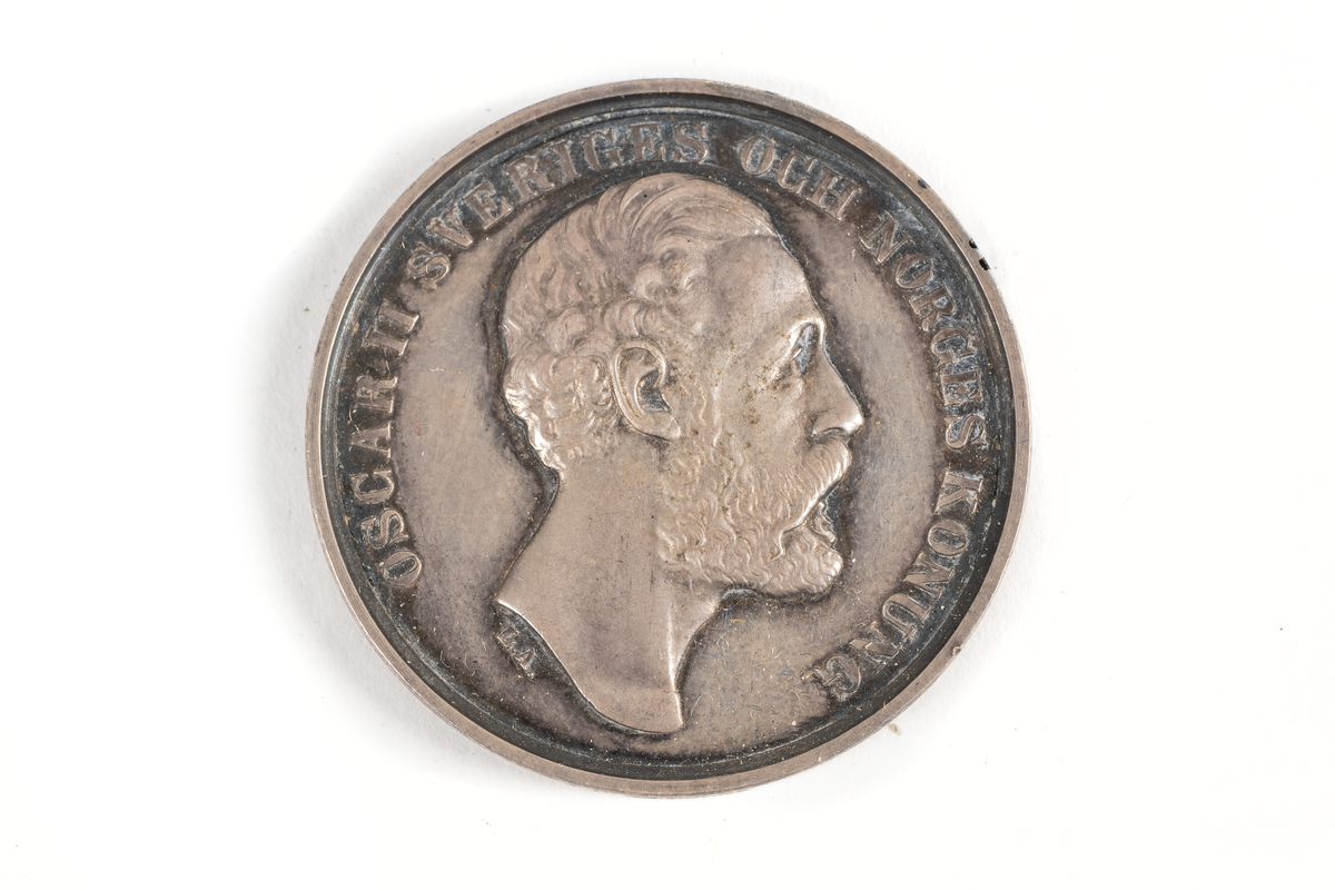 Medalj av silver utdelad av Kalmar läns hushållningssällskap, sannolikt som pris eller belöning för arbete, skicklighet eller prestation inom lantbruk eller liknande.