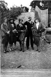 Fire kvinner og en mann på tur nedover en vei. Stilige antre