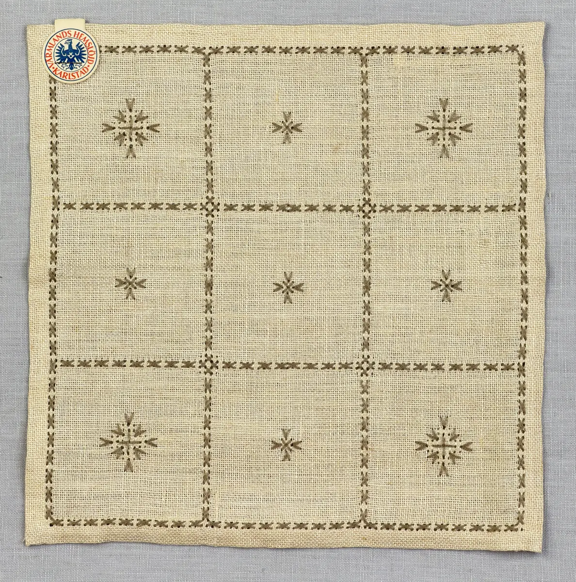 Duk gjord av linneväv med 12tr/cm i tuskaft och broderi utfört med lingarn i myrgång sytt över tre trådar samt moulinègarn i korsstygn och någon typ av tofssöm. Duken har 9mm bred dubbelvikt fåll runt om och sneda hörn fastsydda med kaststygn. 