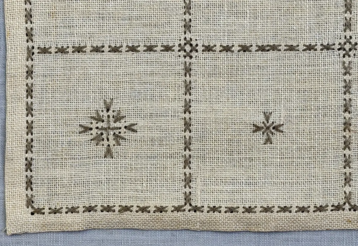 Duk gjord av linneväv med 12tr/cm i tuskaft och broderi utfört med lingarn i myrgång sytt över tre trådar samt moulinègarn i korsstygn och någon typ av tofssöm. Duken har 9mm bred dubbelvikt fåll runt om och sneda hörn fastsydda med kaststygn. 