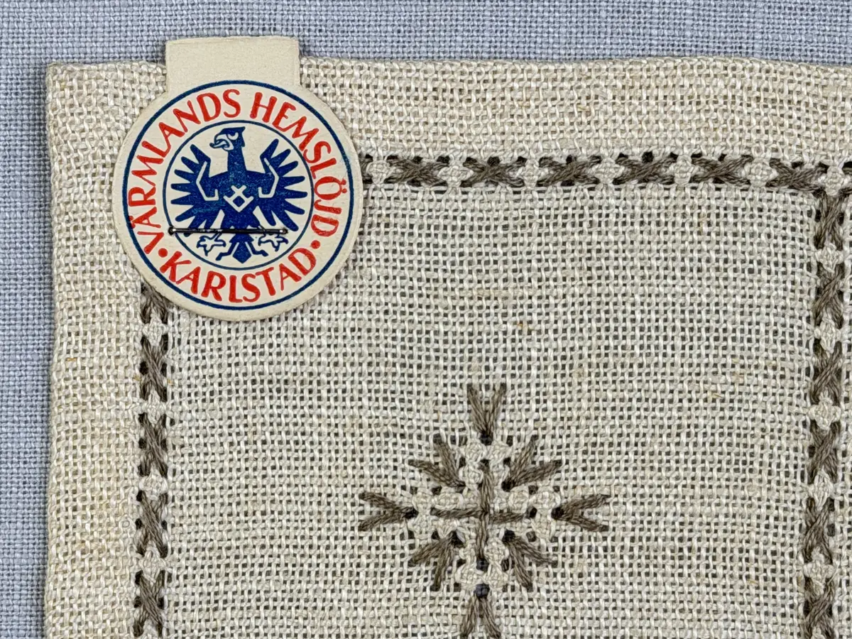 Duk gjord av linneväv med 12tr/cm i tuskaft och broderi utfört med lingarn i myrgång sytt över tre trådar samt moulinègarn i korsstygn och någon typ av tofssöm. Duken har 9mm bred dubbelvikt fåll runt om och sneda hörn fastsydda med kaststygn. 