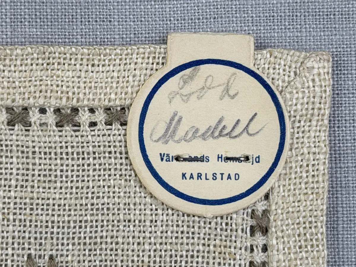 Duk gjord av linneväv med 12tr/cm i tuskaft och broderi utfört med lingarn i myrgång sytt över tre trådar samt moulinègarn i korsstygn och någon typ av tofssöm. Duken har 9mm bred dubbelvikt fåll runt om och sneda hörn fastsydda med kaststygn. 