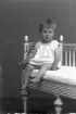 Porträtt av en liten flicka som sitter på en soffa i gustaviansk stil.