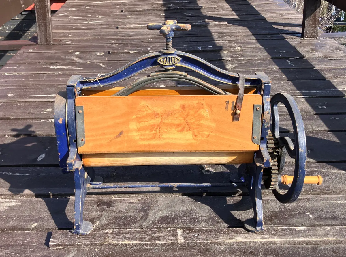 Lenvik/Senja: Finnsnes: Seljestad: Klesrulle/Tøyrulle for bord. Blålakkert 
stål, treplater i laminert tre. Hholdt på plass med lærremmer når
 ikke i bruk.