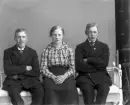 Två tonåriga pojkar och en flicka sitter på soffa i gustaviansk stil.