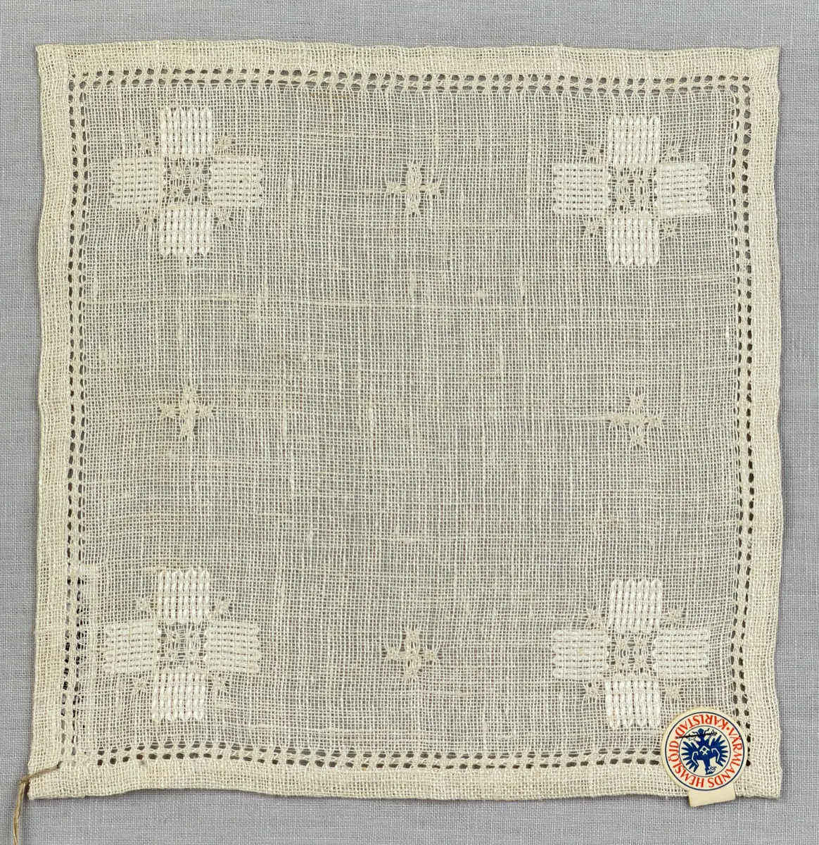 Duk gjord av linneväv med 8tr/cm i tuskaft och broderi utfört med merceriserat bomullsgarn i stoppstygn samt knyppeltråd i slingerstygn och myrgång sydd över fyra trådar. Duken har 9mm bred dubbelvikt fåll runt om och sneda hörn fastsydda med kaststygn.
