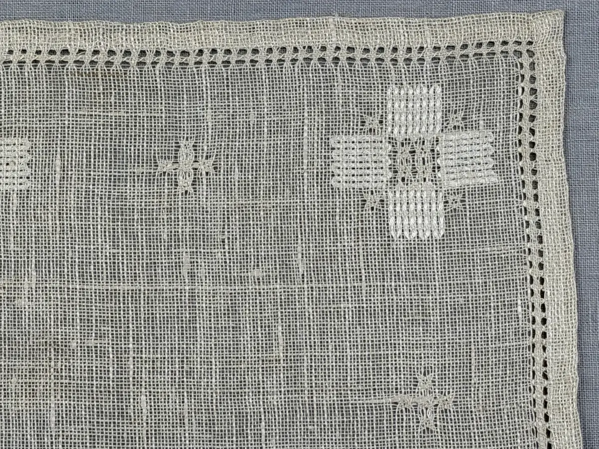 Duk gjord av linneväv med 8tr/cm i tuskaft och broderi utfört med merceriserat bomullsgarn i stoppstygn samt knyppeltråd i slingerstygn och myrgång sydd över fyra trådar. Duken har 9mm bred dubbelvikt fåll runt om och sneda hörn fastsydda med kaststygn.
