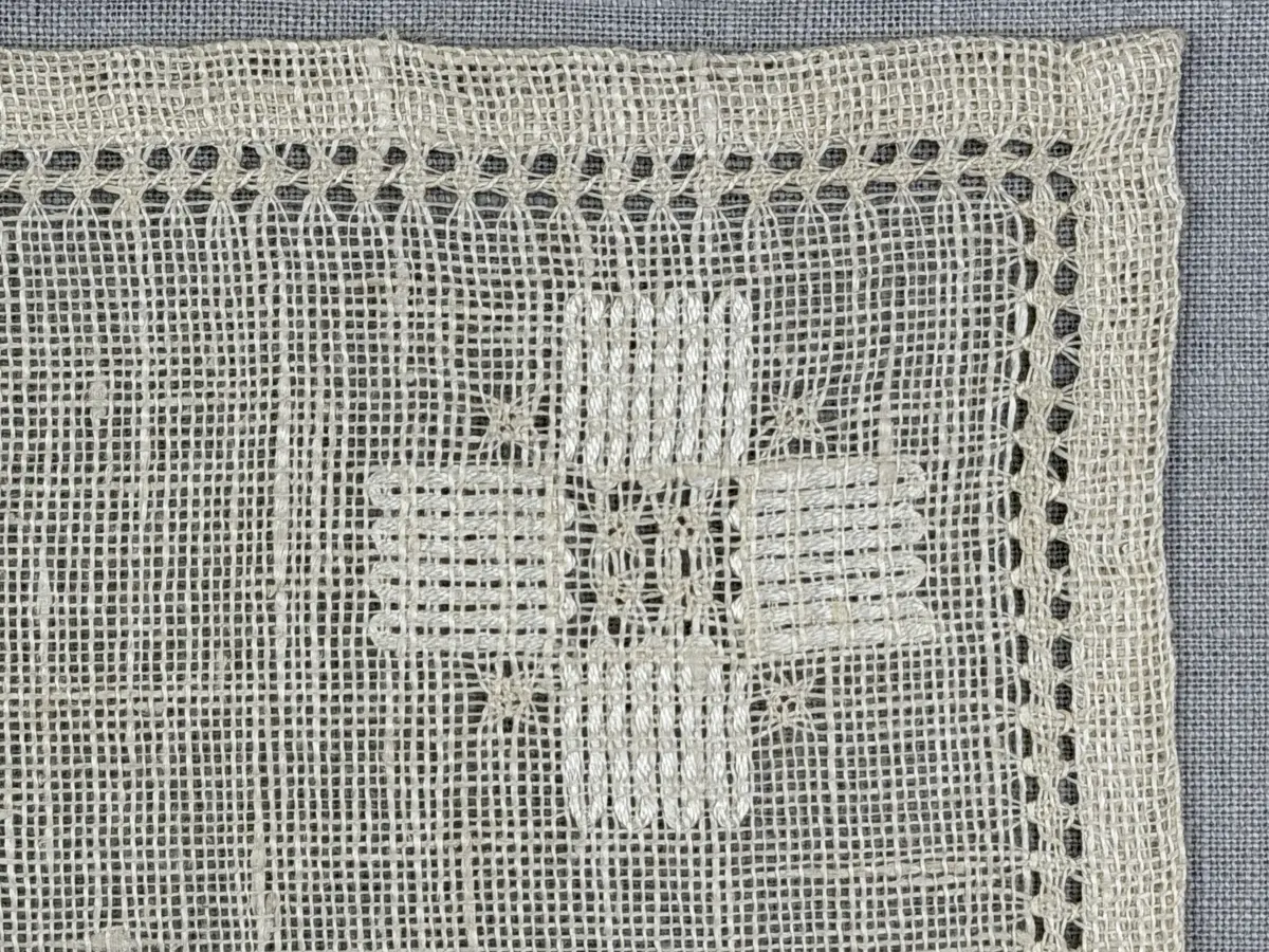 Duk gjord av linneväv med 8tr/cm i tuskaft och broderi utfört med merceriserat bomullsgarn i stoppstygn samt knyppeltråd i slingerstygn och myrgång sydd över fyra trådar. Duken har 9mm bred dubbelvikt fåll runt om och sneda hörn fastsydda med kaststygn.
