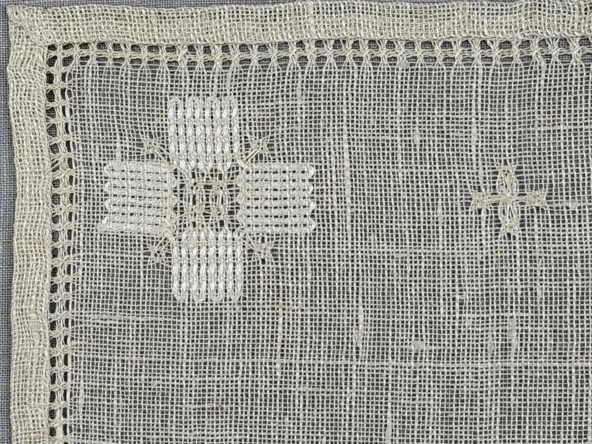 Duk gjord av linneväv med 8tr/cm i tuskaft och broderi utfört med merceriserat bomullsgarn i stoppstygn samt knyppeltråd i slingerstygn och myrgång sydd över fyra trådar. Duken har 9mm bred dubbelvikt fåll runt om och sneda hörn fastsydda med kaststygn.
