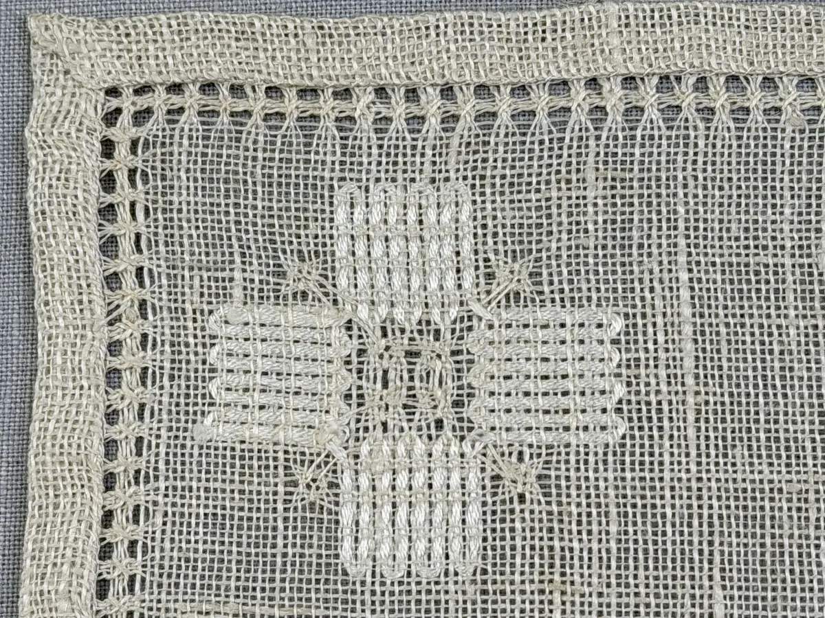 Duk gjord av linneväv med 8tr/cm i tuskaft och broderi utfört med merceriserat bomullsgarn i stoppstygn samt knyppeltråd i slingerstygn och myrgång sydd över fyra trådar. Duken har 9mm bred dubbelvikt fåll runt om och sneda hörn fastsydda med kaststygn.
