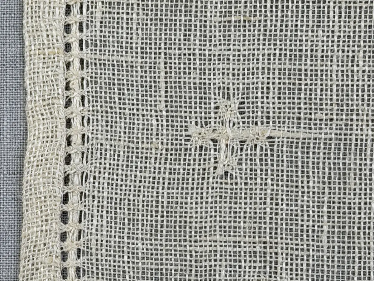 Duk gjord av linneväv med 8tr/cm i tuskaft och broderi utfört med merceriserat bomullsgarn i stoppstygn samt knyppeltråd i slingerstygn och myrgång sydd över fyra trådar. Duken har 9mm bred dubbelvikt fåll runt om och sneda hörn fastsydda med kaststygn.
