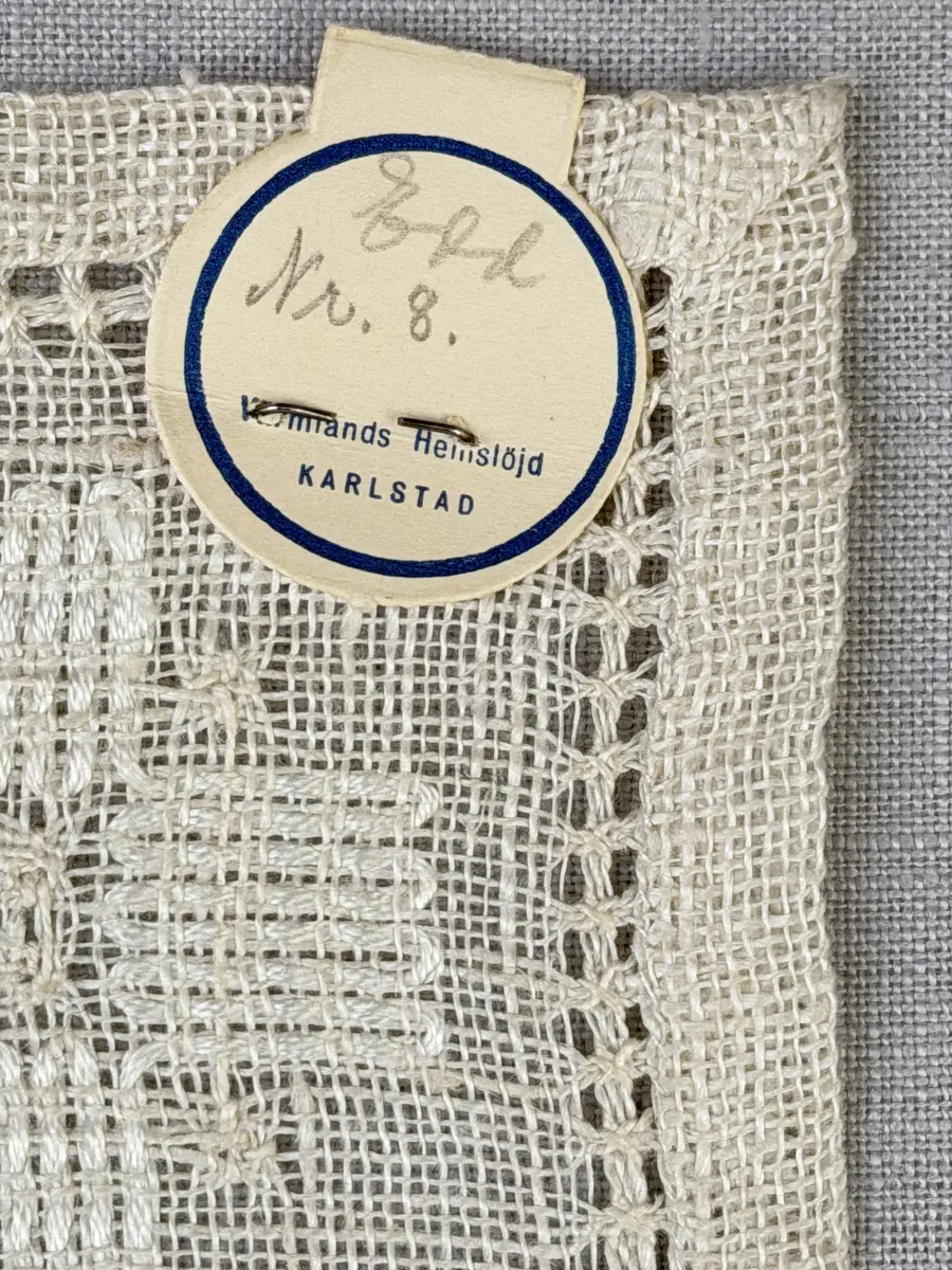 Duk gjord av linneväv med 8tr/cm i tuskaft och broderi utfört med merceriserat bomullsgarn i stoppstygn samt knyppeltråd i slingerstygn och myrgång sydd över fyra trådar. Duken har 9mm bred dubbelvikt fåll runt om och sneda hörn fastsydda med kaststygn.
