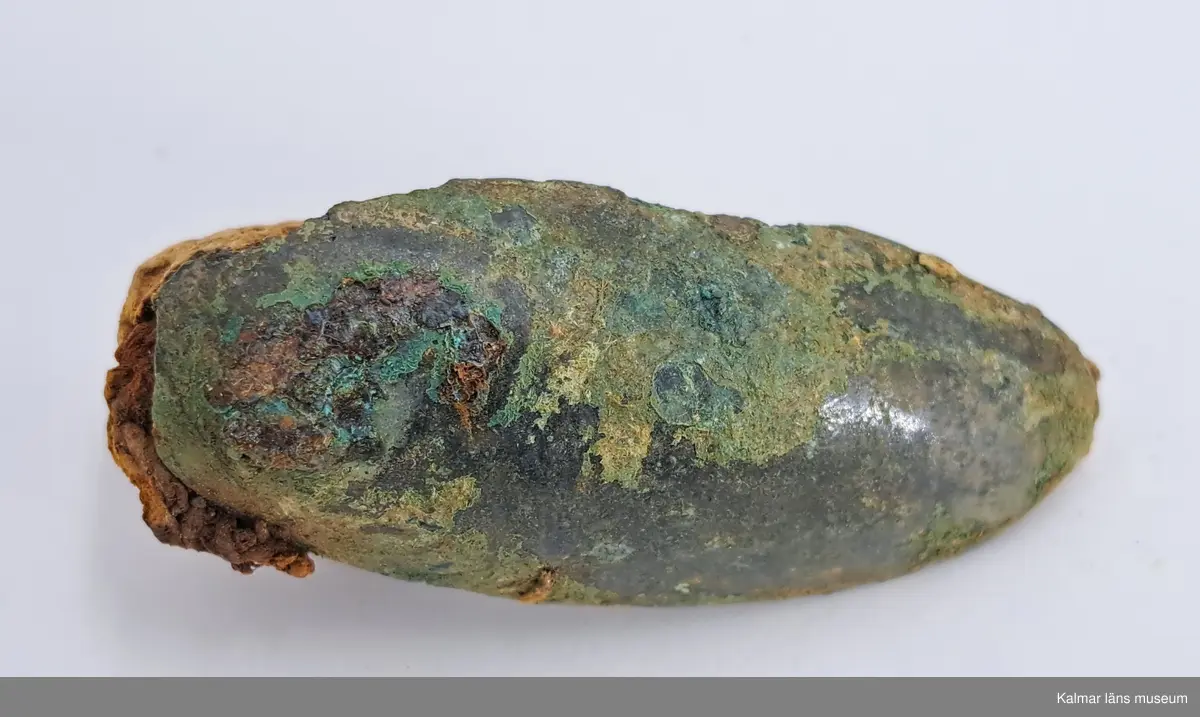 KLM 46818:3359. Spännbuckla. Helt slät och oornerad spännbuckla av brons. Med textilfragment som sitter kvar på undersidan.