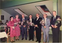 Fire kvinner og fem menn med kvar sin blomsterbukett. På bak