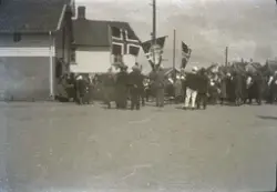 Ei lita folkemengd med norske flagg og ein fane som det står
