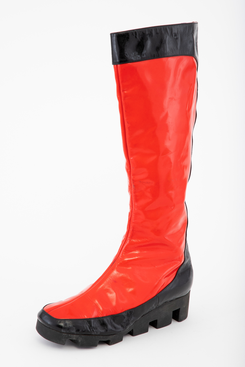 Én venstre, knehøy støvel i rød vinyl med kanting av svart. Kraftig, tagget, svart naturgummisåle og glidelås bak.