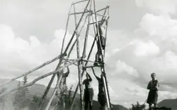 Menn bygger et tårn av stokker. Mulig speideraktivitet