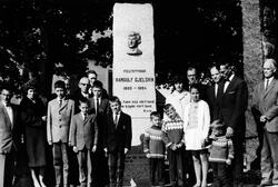 En gruppe bestående av kvinner, menn og barn står ved bautae