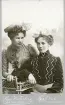 Porträtt av två kvinnor i tidstypisk klädsel från sekelskiftet 1900.
