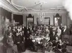 Gruppfoto vid Hans Anders Mattssons 50-årsfest i Galoschbolagets hus ? Mannen som sitter till höger om bordet är H. A. Mattsson, hans hustru Josa (Josefina) snett ovanför honom till höger i ljus klänning, sonen Fredrik till höger om honom. sonen Knut samt sonen Gustav sittande nedanför på golvet (enligt text i album).