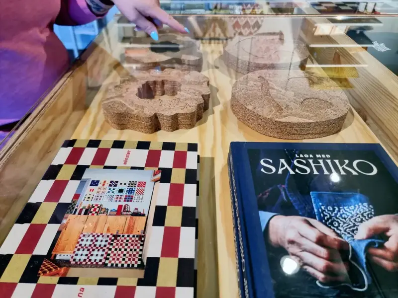 Montrar i museibutiken visar vackra böcker, en hand med turkos naglar pekar.