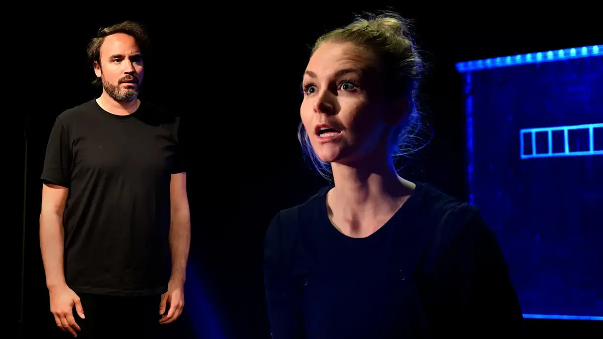 to skodespelarar i mørke t-skjorter står på ei mørk scene.