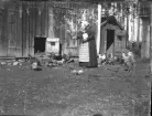 En okänd kvinna på en okänd gård matar höns.