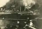 Bilden visar hur besättningen ror bort från den eldhärjade tyska linjeångaren S/S COLUMBUS i livbåtar.