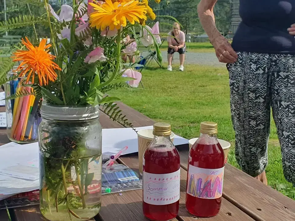 Bord med blomster og egenprodusert saft på flasker