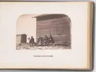 Vy över vinterkvarteret Polhem i Mosselbukten på Spetsbergen, uppfört under Spetsbergsexpeditionen 18721873 som leddes av Adolf Erik Nordenskiöld. Fyra expeditionsmedlemmar och en hund sitter framför trähuset.